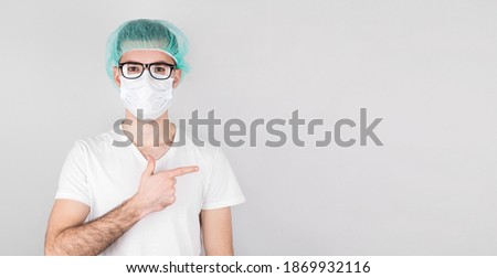 American surgeon doctor man over gray background looking and pointing to the side.