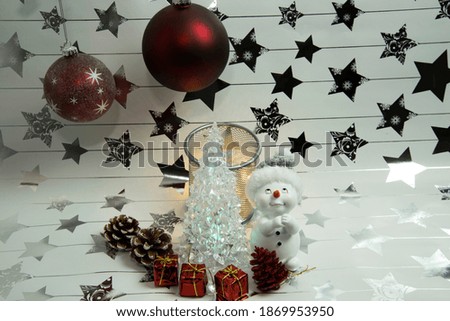 A snowman with presents and a Christmas tree.Christmas scene on a white background with silver stars.