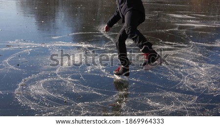 A young man is ice skating on a pond on a beautiful sunny day. Selective focus.