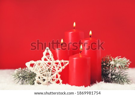 Christmas candles with star and fir tree branches on red background