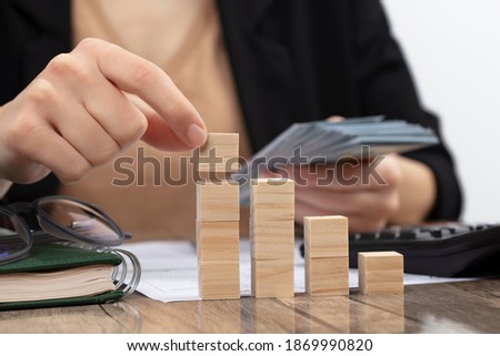 Business woman accounting and banker doing calculations. Concept of success rising with wooden cube.