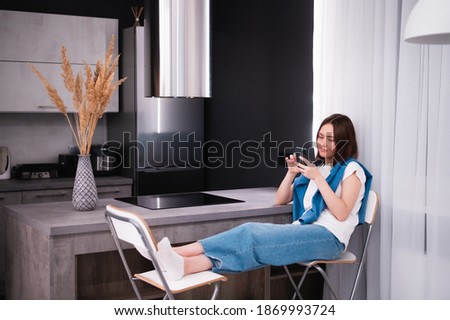 Shopping or ordering delivery online with mobile smart phone. Happy young woman using cellphone at home while sitting on a kitchen.