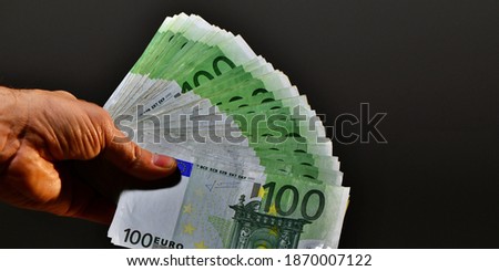 A man's hand shows 10,000 euros in one hundred 100 euro banknotes