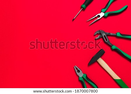A set of quality green building tools to repair a car or a house on a red background. Do it yourself instruments. Banner for advertising construction shop with copy space. Business card.