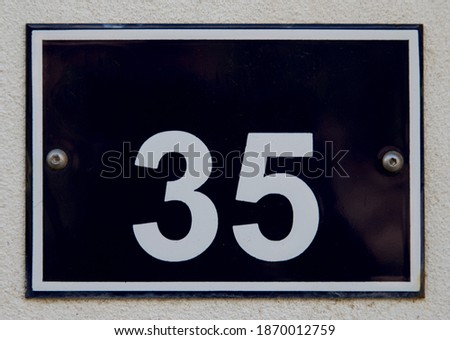 Detail of an iron plate painted in blue with door number 35.