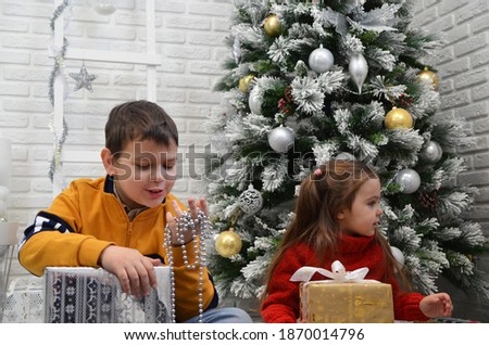 Happy little kids decorate Christmas tree in beautiful living room with traditional fire place. Children opening presents on Xmas eve. open gifts, play with toys new year