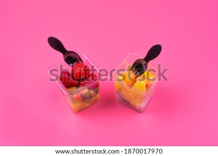 fruit dessert in a transparent square cup, pink background, top view