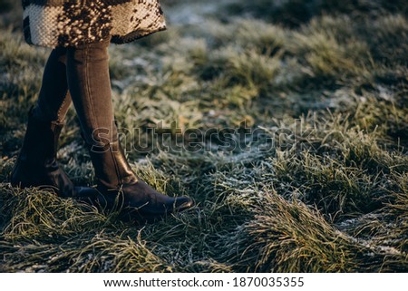 Female feet on the grass covered with hoarfrost