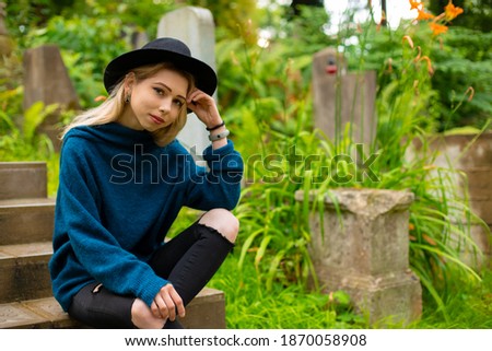 simple female portrait photography of young attractive teenager girl sitting on stair in cemetery green outdoor environment space 