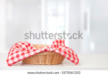 Wicker basket with red checkered tablecloth on the table