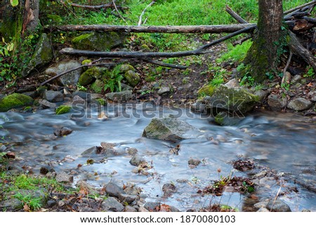 wooden log fence next to small river with silk effect in autumn