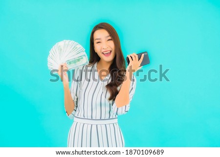 Portrait beautiful young asian woman with a lot of cash and money on blue background