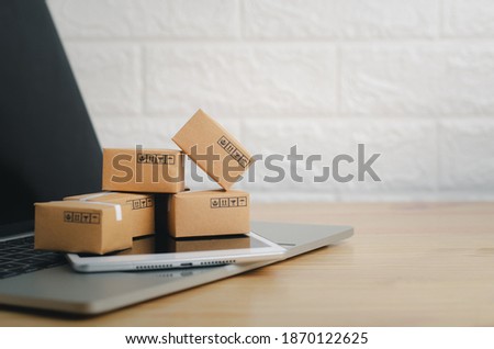 Brown paper boxs with laptop on wood table in office background.Easy shopping with finger tips for consumers.Online shopping and delivery service concept.