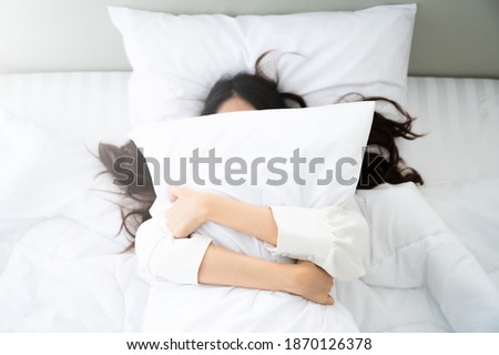 Happy asian young woman hug pillow in bed in the morning Royalty-Free Stock Photo #1870126378