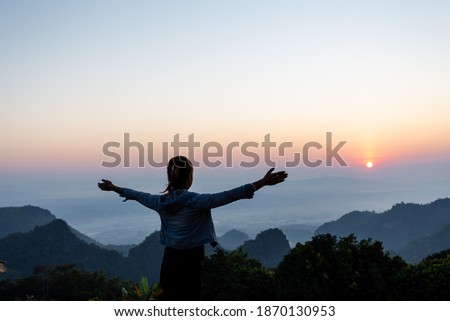 Back view of a happy female tourist watching the sunset