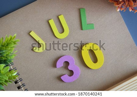 July 30, Cover design in natural concept with a brown notebook and colorful wooden alphabet.