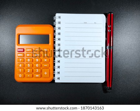 Selective focus.Copy space and text space on notebook with pen and calculator with black background.Business and education concept.