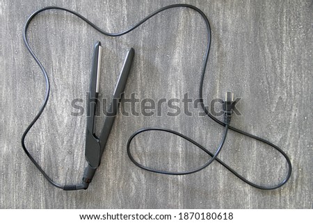 
hair straightener, stylist's utensil on vintage wooden gray background