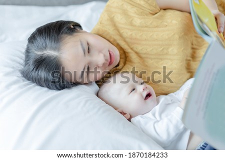 mother and her son reading book in a bed before sleep. Familly story telling concept.
