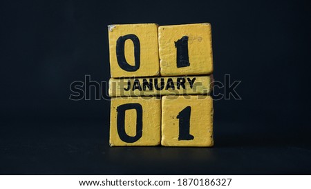 Wooden block calendar with focus on 01 January 01. Black background