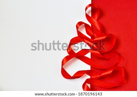 Christmas tree made from red ribbon on a red-white background. Creative concept. Copy space, flat lay. New year greeting card.