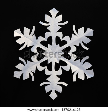 White paper snowflake on black background. Handmade new year decoration