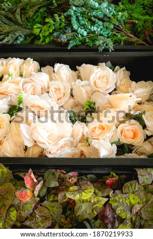 Top view of plastic containers filled with plastic roses and leaves to be used for decoration or styling a wedding reception.