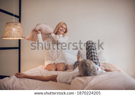 Good mood. Married couple having fun in bedroom and looking joyful