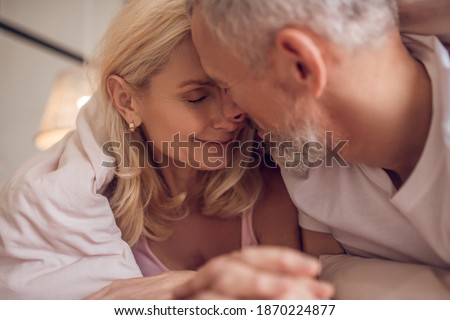 Happy morning. Middle-aged couple having romantic moment in bedroom