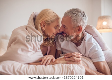 Happy morning. Middle-aged couple having romantic moment in bedroom