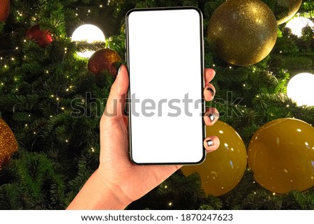 Close up hand holding phone isolated on white background with Illuminated  decoration of  Christmas tree. Flat layout for Christmas festival background concept.