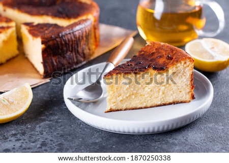 Piece of San Sebastian Basque Cheesecake on the plate on a table with lemon and a cup of tea Royalty-Free Stock Photo #1870250338