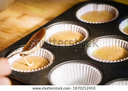 Woman filling muffin molds with a spoon.
