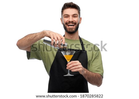 alcohol drinks, people and job concept - happy smiling barman in black apron with shaker and glass preparing martini cocktail over white background Royalty-Free Stock Photo #1870285822