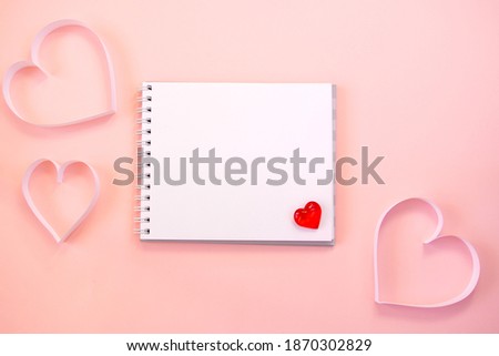 Paper cut hearts, notepad on pastel pink background. Composition for Valentine's Day, postcard. Flat lay, top view, copy space.
