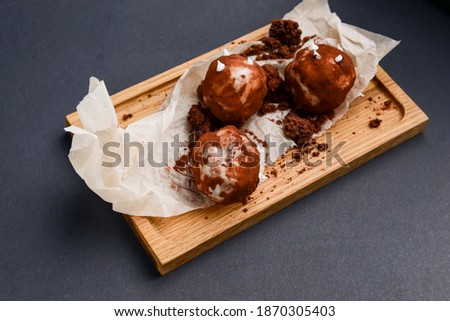 Chocolate potato dessert served on a rustic wooden board over black background. Sweet dessert for tea or coffee time.