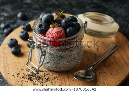 Board with jar of delicious chia pudding on black smokey table