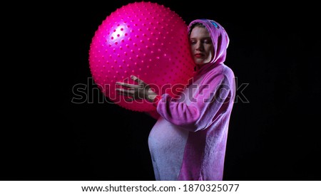 
Girl in pink suit, woman on black isolated background, pregnant with pink ball