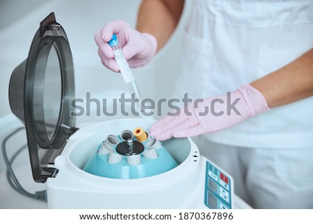 Cropped photo of a woman doctor placing a tube into the platelet-rich plasma centrifuge machine Royalty-Free Stock Photo #1870367896