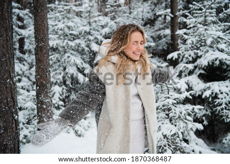 Beautiful blonde walks in the Park in winter, snow is everywhere.