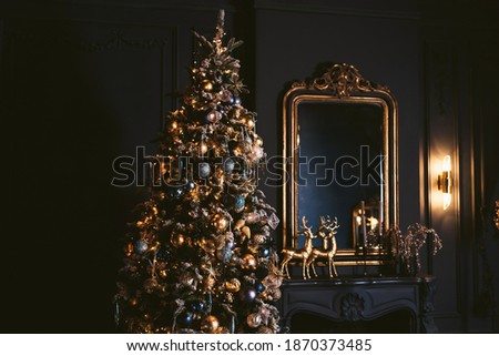 Interior of cozy room decorated in Christmas Happy new Year style. Fireplace. No people. An empty sofa, Christmas tree with presents under it. Selective focus. Happy NY mood