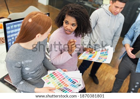 African graphic designer discusses the color scheme of a website with a colleague