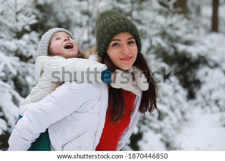 Young family for a walk. Mom and daughter are walking in a snowy park.