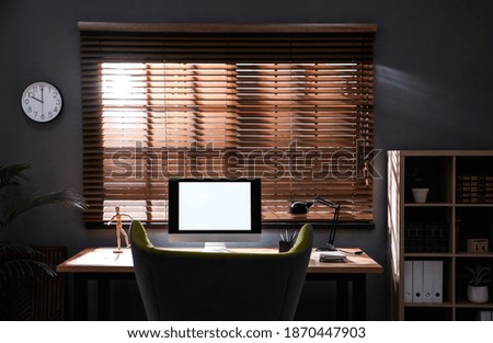 Stylish room interior with modern computer and comfortable office chair