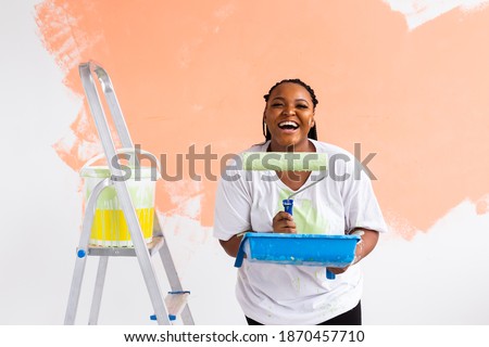 Smiling african american woman painting interior wall of home. Renovation, repair and redecoration concept. Royalty-Free Stock Photo #1870457710