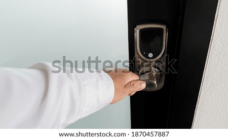 The hand that is opening the door with a handle knob