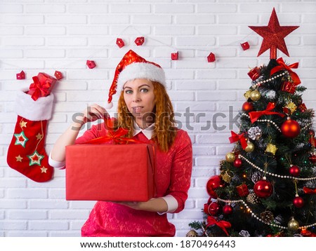 Christmas holidays. A girl in a red dress unfolds a box with a gift. Background and texture.