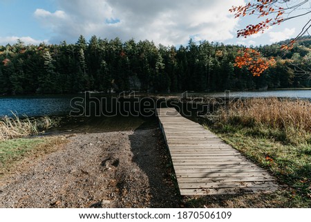 Adirondacks Mountains with spring water and blue sky scene. Green untouched forest landscape. Foliage in Adirondack mountains. Upstate New York. Dock by the lake. 