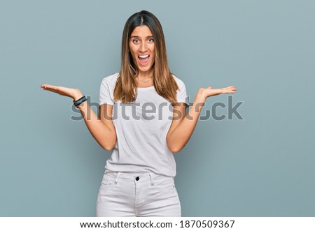 Young woman wearing casual white t shirt celebrating victory with happy smile and winner expression with raised hands 
