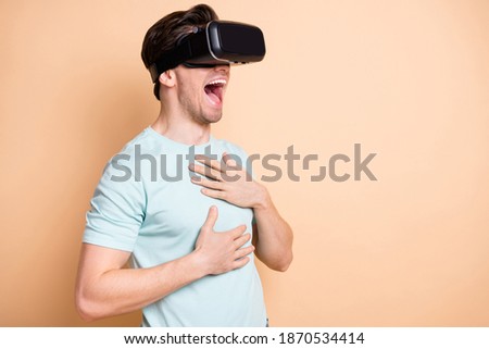 Profile side view portrait of nice cheerful guy wearing vr helmet laughing having fun isolated over beige pastel color background